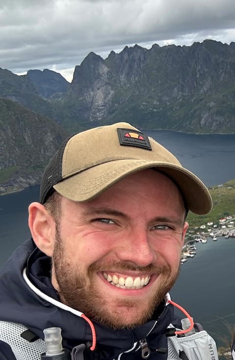 Jonas Lindemann mit Kappe, hinter ihm Berge und ein Fjord in Norwegen